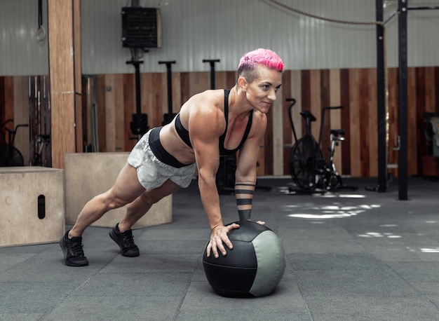 Wysportowana Muskularna Kobieta Robi Pompki Z Piłeczkami Lekarskimi W Nowoczesnej Siłowni. Crossfit, Trening Funkcjonalny