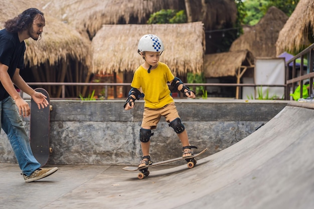 Wysportowany chłopiec uczy się jeździć na deskorolce z trenerem w skateparku Edukacja dzieci sport