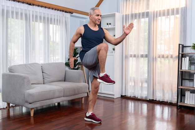 Wysportowany i sportowy starszy mężczyzna pozuje do biegania w domu Zdrowy, dopasowany styl życia jako koncepcja ćwiczeń w domu po przejściu na emeryturę Clout