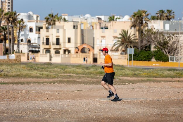 Wysportowany mężczyzna biegający w parku ze słuchawkami w słoneczny letni dzień Zdrowy styl życia Aktywni dorośli mężczyźni uprawiają jogging