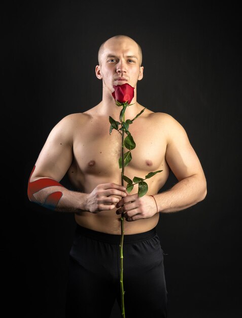 Wysportowany mężczyzna trzymający nagą czerwoną różę dla teipowego kulturysty, romantycznego kochanka LGBT In