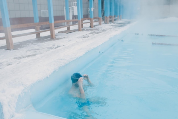 Wysportowany pływak trenujący pływanie w otwartym zimowym basenie z mgłą Koncepcja geotermalnego spa na świeżym powietrzu