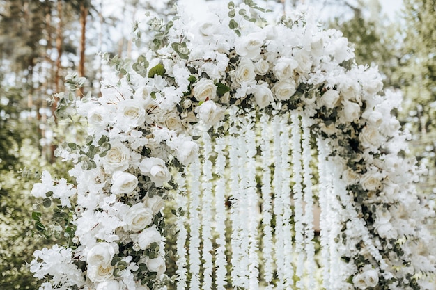 Wystrój łuku z białymi kwiatami na ceremonię ślubną w przyrodzie