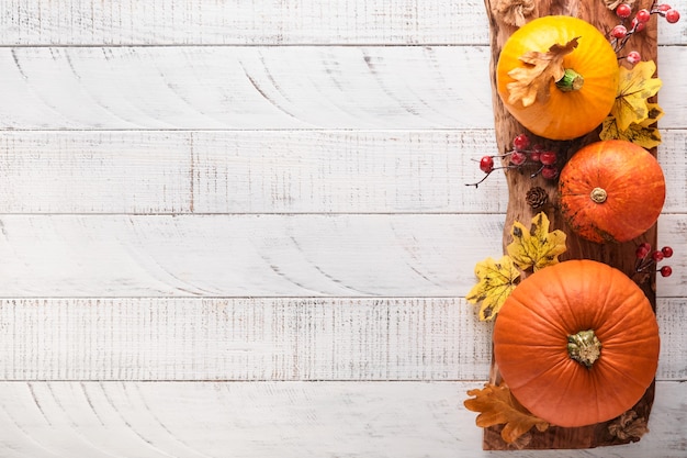 Zdjęcie wystrój z dyni, jagód i liści na białym rustykalnym drewnianym tle. koncepcja święta dziękczynienia lub halloween. widok z góry świąteczna jesienna kompozycja z miejsca na kopię.