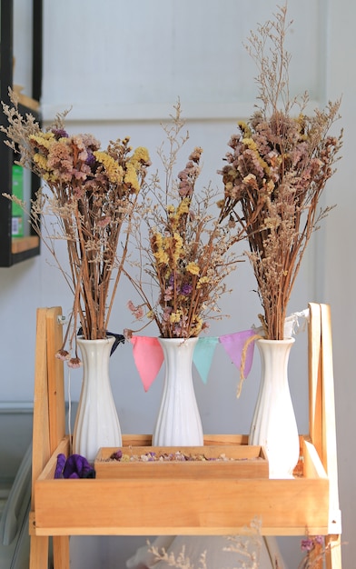 Zdjęcie wysuszeni kwiaty w wazowej dekoraci na drewnianej półce przy kawiarnią.