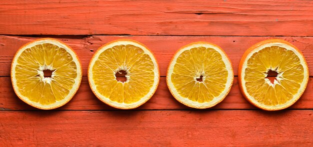 Zdjęcie wysuszeni pomarańcze plasterki na pomarańczowym drewnianym tle. widok z góry.