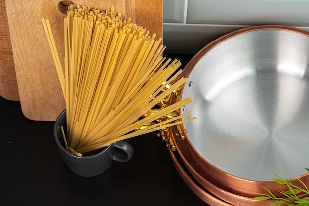 Zdjęcie wysuszyć spaghetti na blacie kuchennym z bliska naczynia do gotowania