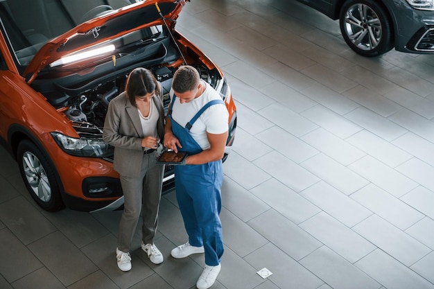 Wyświetlanie Wyników Pracy Mężczyzna Naprawiający Kobiece Auto W Pomieszczeniu Profesjonalna Obsługa