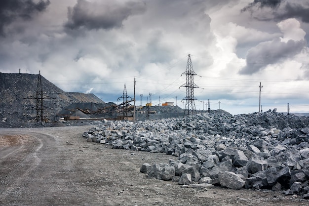 Wysypiska kamieni, linie energetyczne i kruszarki w kamieniołomie przy pochmurnej pogodzie