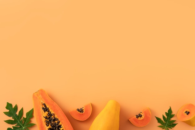 Wytnij papaję na pomarańczowym tle stołu, aby uzyskać widok z góry koncepcji projektu owoców tropikalnych