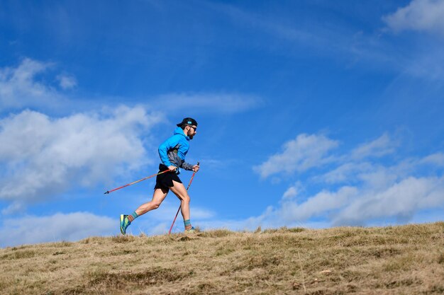 Zdjęcie wytrzymałościowy wyścig górski mężczyzna z kijami wspinaczkowymi