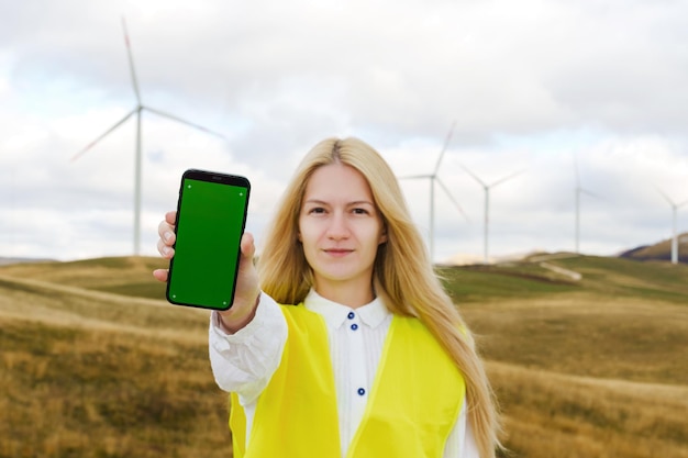 Wytwarzanie energii z turbin wiatrowych Inżynier wyciąga telefon komórkowy z zielonym ekranem do aparatu Selektywna koncentracja na telefonie