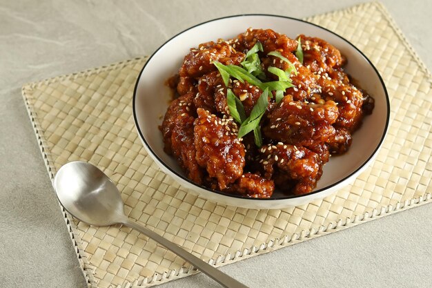 Yangnyeom Tongdak, koreański smażony kurczak z pikantnym sosem i sezamem. Podawany na białym talerzu