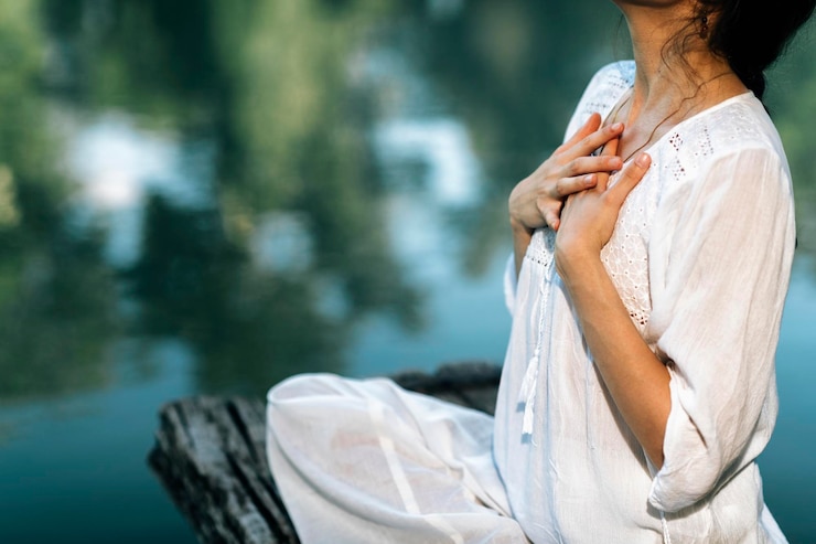 Zdjęcie yoga retreat pokojowa młoda kobieta siedząca w pozycji lotosu i medytująca nad jeziorem