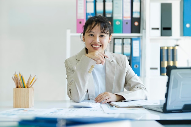 Yong Asian pewna bizneswoman uśmiecha się i patrzy na kamerę