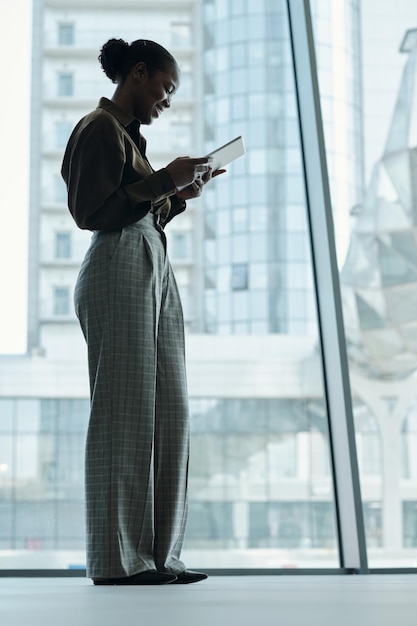 Young african american businesswoman in smart casualwear using tablet