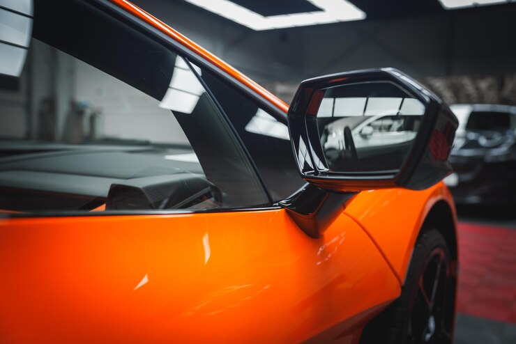 Z bliska Lamborghini Revuelto boczne lustro i pomarańczowa karoseria