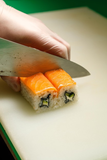 Z bliska widok rąk szefa krojenia rolki sushi