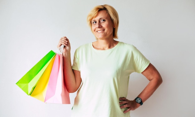 Zdjęcie z bliska zdjęcie szczęśliwej dojrzałej kobiety w średnim wieku trzyma w domu kolorowe torby na zakupy zakupy online płatność klienta zniżka na zakupy bezprzewodowe