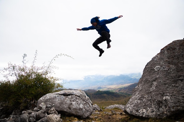 Z dołu widok wysportowanego mężczyzny skaczącego ze skały na skałę podczas parkour