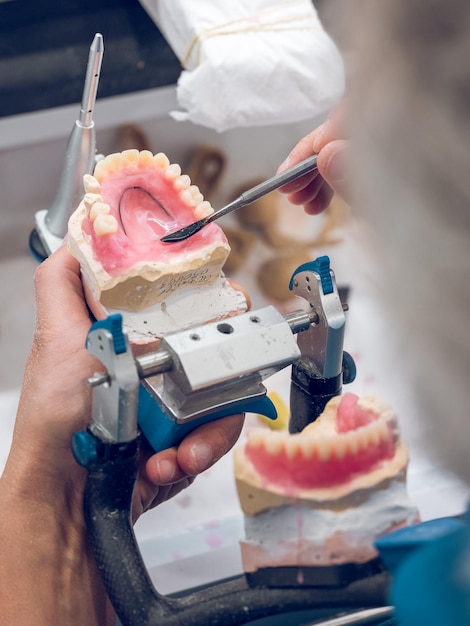 Z góry nierozpoznawalny ortodonta używający szpatułki dentystycznej do kształtowania protezy w laboratorium