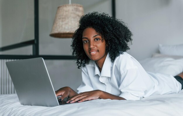 Z laptopem Młoda afroamerykanka z kręconymi włosami w domu w domu