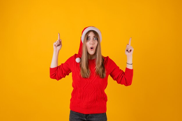 Z podnieceniem kobieta wskazuje palce przy kopii przestrzenią jest ubranym Santa kapelusz i czerwonego pulower