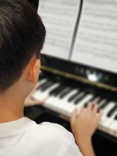Zdjęcie z tyłu chłopiec grający na pianinie