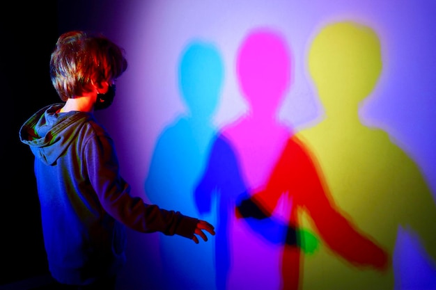 Zdjęcie z tyłu chłopiec stojący przy oświetlonej ścianie