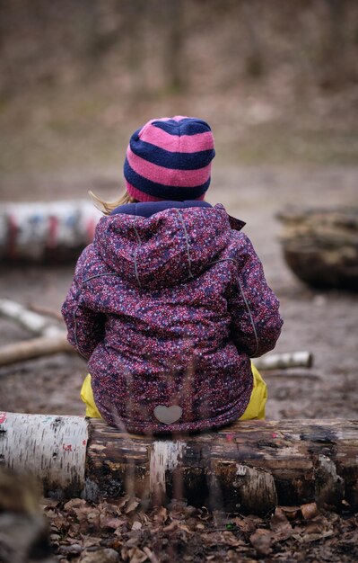 Zdjęcie z tyłu dziewczyna siedząca na drewnie w lesie