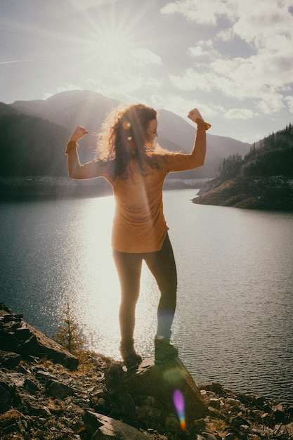 Zdjęcie z tyłu pełna długość kobiety zgiętej mięśniami na jeziorze w słoneczny dzień
