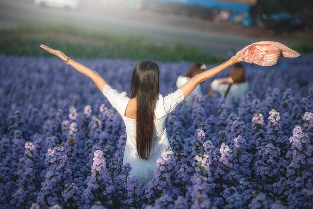 Zdjęcie z tyłu piękna kobieta stojąca z podniesionymi rękami na polu lawendowych kwiatów