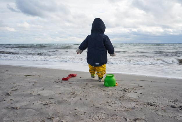 Zdjęcie z tyłu widok chłopca chodzącego po brzegu na plaży