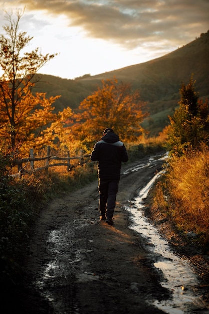 Zdjęcie z tyłu widok człowieka idącego po drodze pośród drzew jesienią