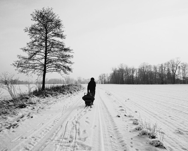 Zdjęcie z tyłu widok człowieka idącego po pokrytym śniegiem polu
