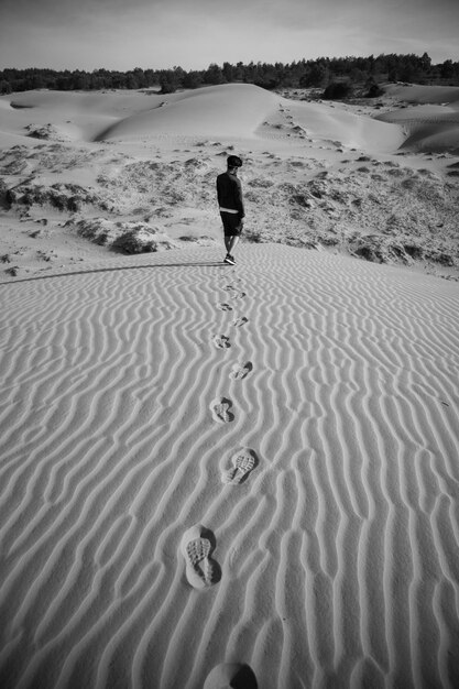 Zdjęcie z tyłu widok człowieka stojącego na piasku na pustyni