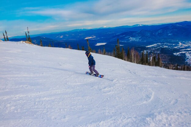 Zdjęcie z tyłu widok człowieka z deską snowboardową stojącego na pokrytym śniegiem terenie