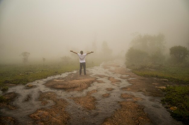 Zdjęcie z tyłu widok człowieka z wyciągniętymi ramionami stojącego na lądzie