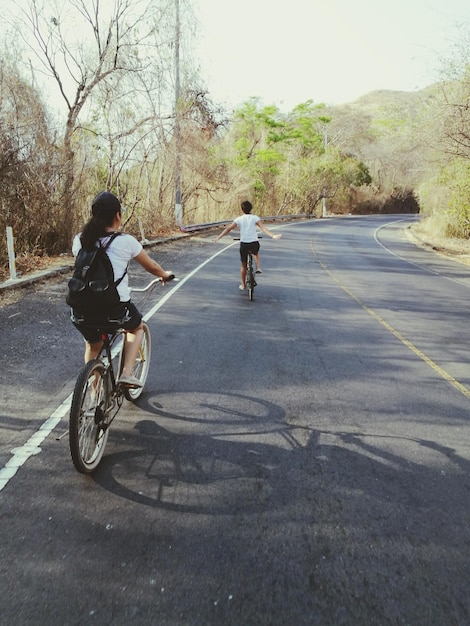 Zdjęcie z tyłu widok kobiet jeżdżących na rowerze po drodze