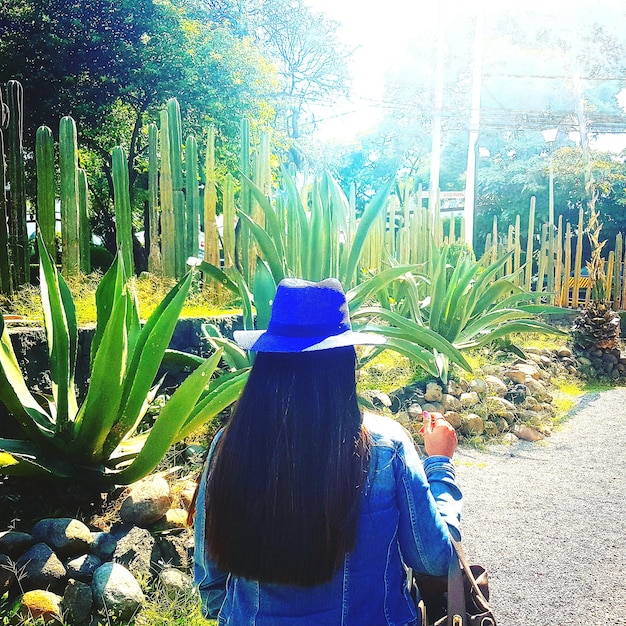 Zdjęcie z tyłu widok kobiety idącej po drodze obok roślin w parku