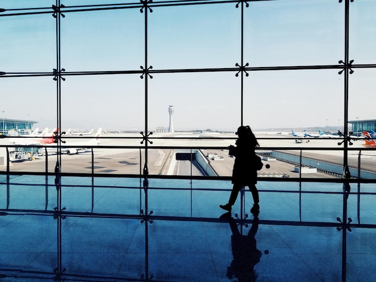 Zdjęcie z tyłu widok kobiety na pasie startowym lotniska na tle nieba