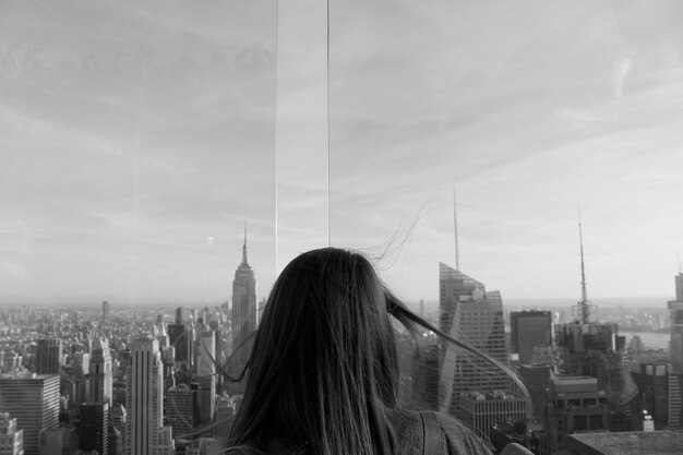 Zdjęcie z tyłu widok kobiety patrzącej na nowoczesne budynki w mieście na tle nieba