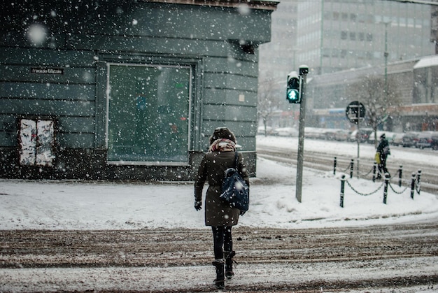 Z tyłu widok kobiety przechodzącej przez ulicę w zimie