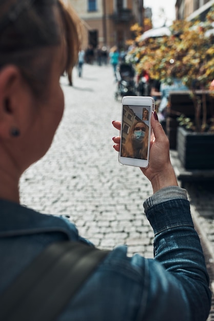 Z tyłu widok kobiety rozmawiającej w rozmowie wideo stojącej na zewnątrz