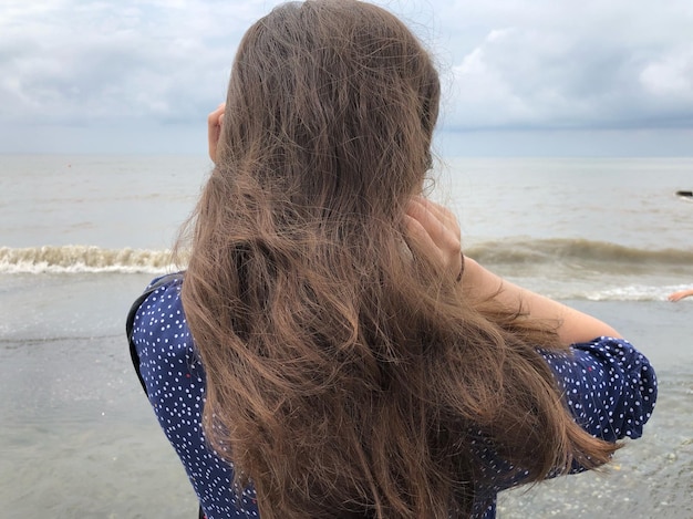 Zdjęcie z tyłu widok kobiety stojącej na plaży na tle nieba