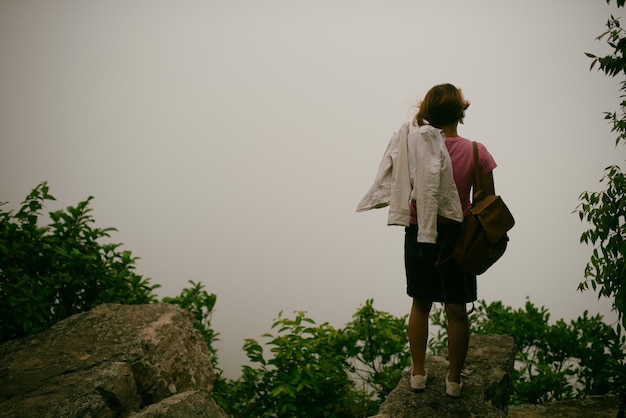 Zdjęcie z tyłu widok kobiety stojącej na skale na tle nieba