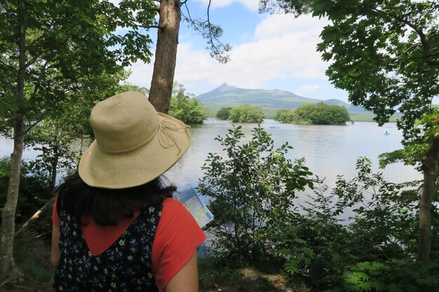 Zdjęcie z tyłu widok kobiety w kapeluszu nad jeziorem