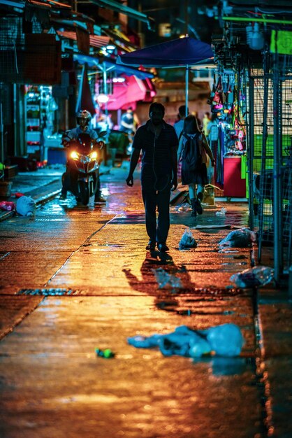 Zdjęcie z tyłu widok ludzi idących po oświetlonej ulicy w nocy