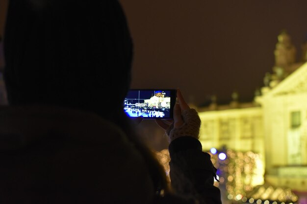 Zdjęcie z tyłu widok mężczyzny fotografującego oświetlony smartfon w nocy