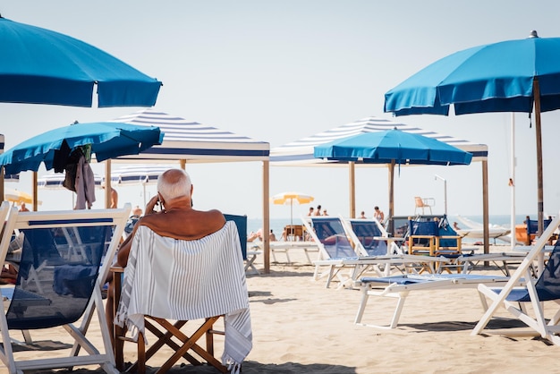 Z tyłu widok starszego mężczyzny siedzącego na krześle na plaży